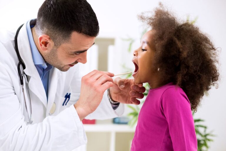 Pediatrics-Tonsil-Infection-exam child with mouth open as doctor inspects tonsils